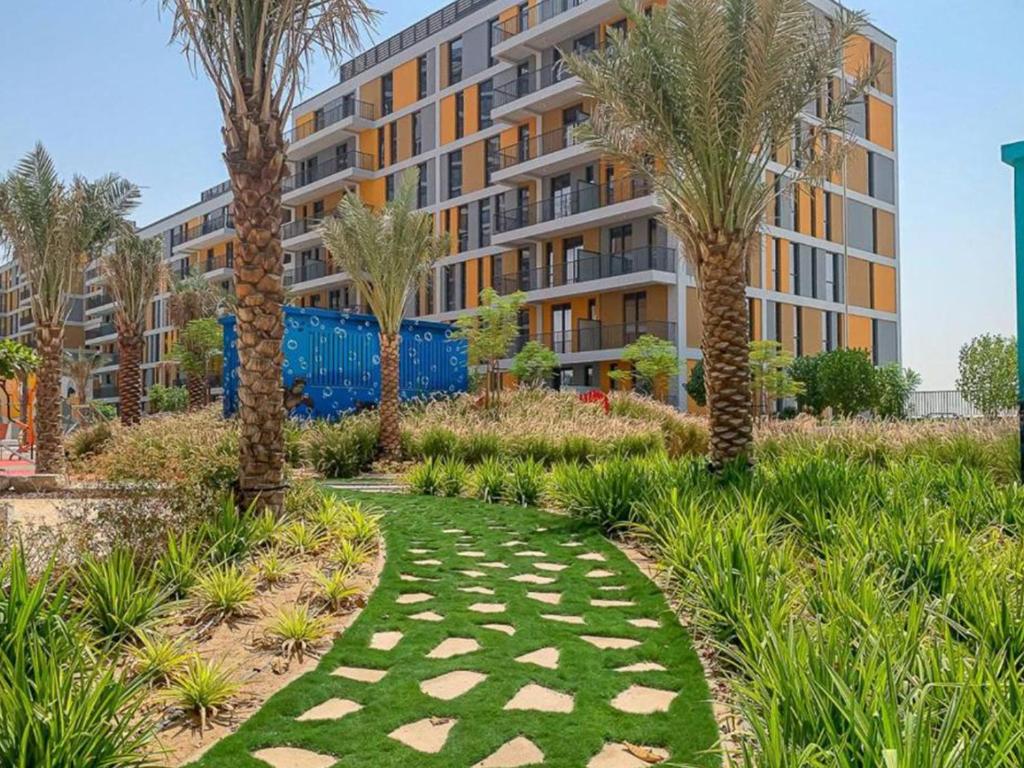 un jardín con palmeras y un edificio en ANW Vacation Homes - One bedroom apartment Afnan 4 Midtown Dubai Production City en Dubái