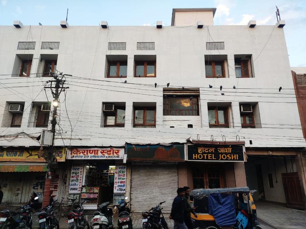 a large white building with motorcycles parked in front of it at Hotel Joshi in Bikaner
