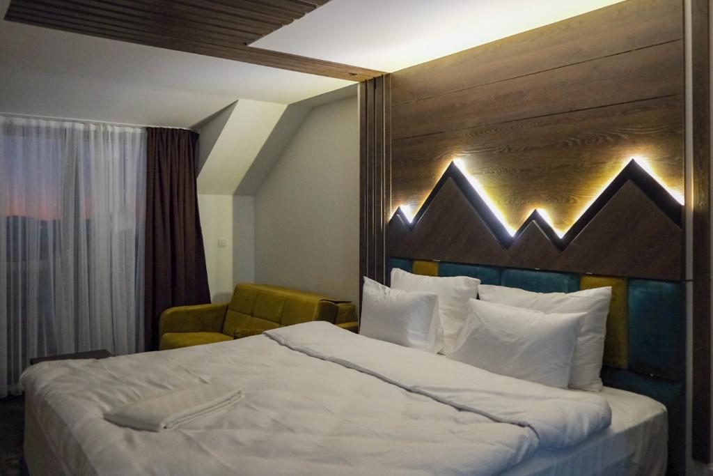 a bedroom with a large bed with a wooden headboard at Harmonija Resort - Harmonia Palace in Kopaonik