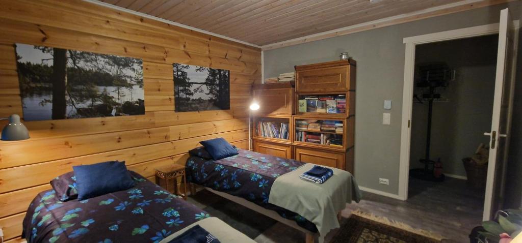 a bedroom with two beds and a wooden wall at #casakivicco in Leppävirta