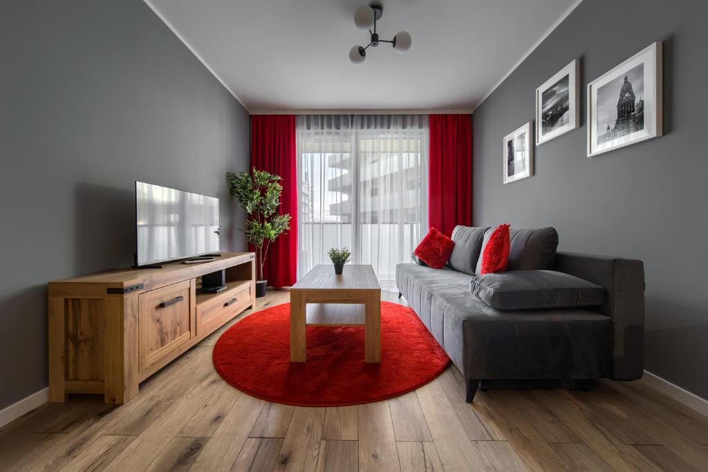salon z kanapą i czerwonym dywanem w obiekcie Central Park Red Apartment we Wrocławiu