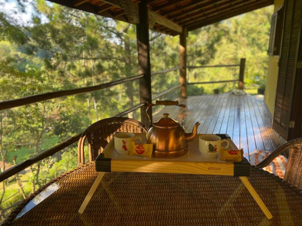 einen Wasserkocher und Tassen auf einem Tisch auf einer Veranda in der Unterkunft Chácara das Araucárias in São Francisco Xavier