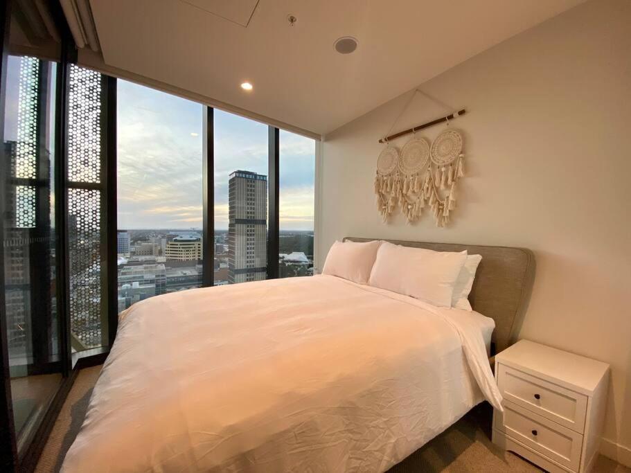 een slaapkamer met een wit bed en een groot raam bij Peaceful & Relaxing City Escape @ Rundle Mall in Adelaide