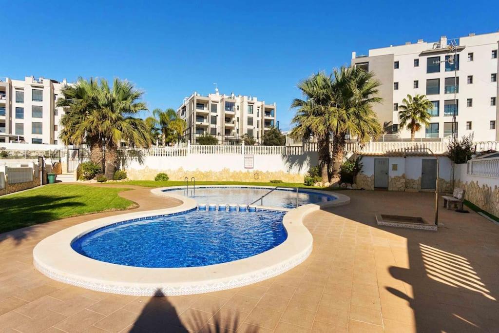 een zwembad in een tuin met palmbomen en gebouwen bij HE Panorama Golf Villamartín in Campoamor