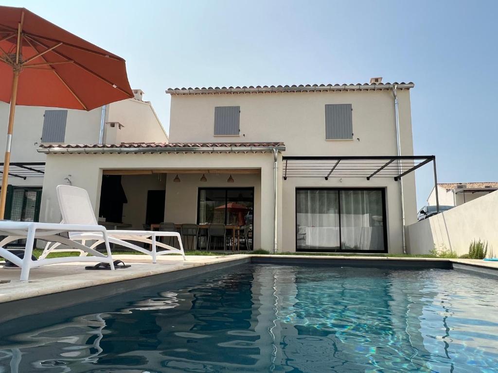 ein Haus mit einem Pool, 2 Stühlen und einem Sonnenschirm in der Unterkunft Villa Hélène in Malaucène