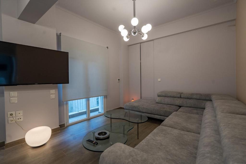 a living room with a large couch and a flat screen tv at Luxury Serenity in Piraeus
