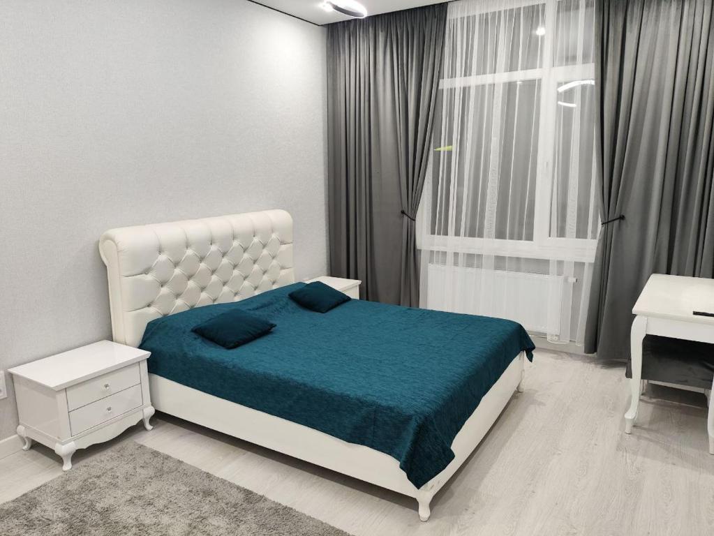 a white bedroom with a bed and a window at ЖК Бухар Жырау in Astana
