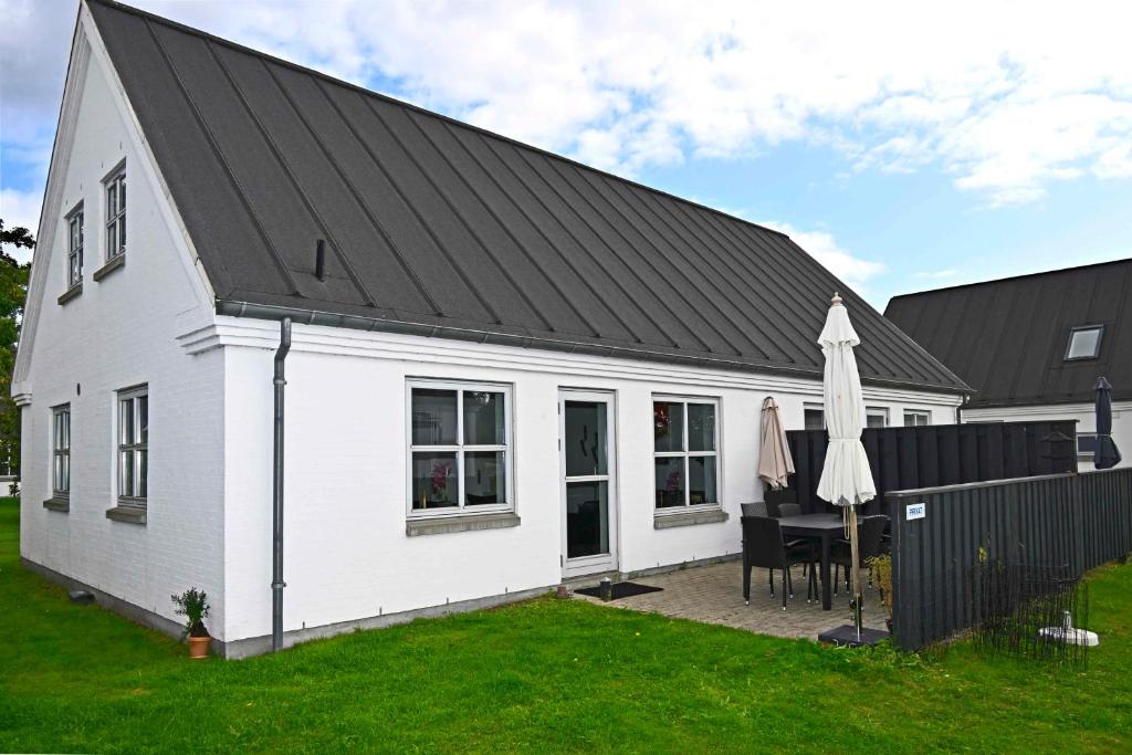 a white house with a black roof and a table at Charming House By The Baltic Sea in Bøtø By