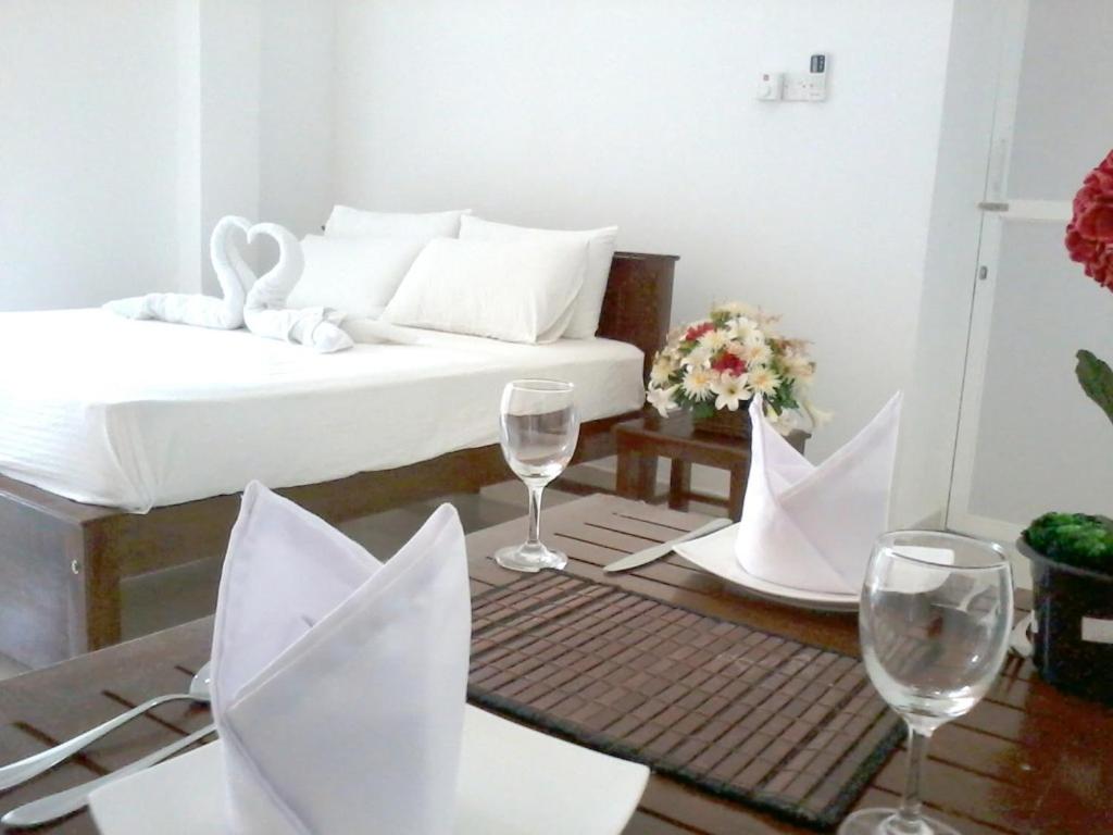 a room with a bed and two wine glasses at Vintop Hotel & Homestays Gampaha in Gampaha