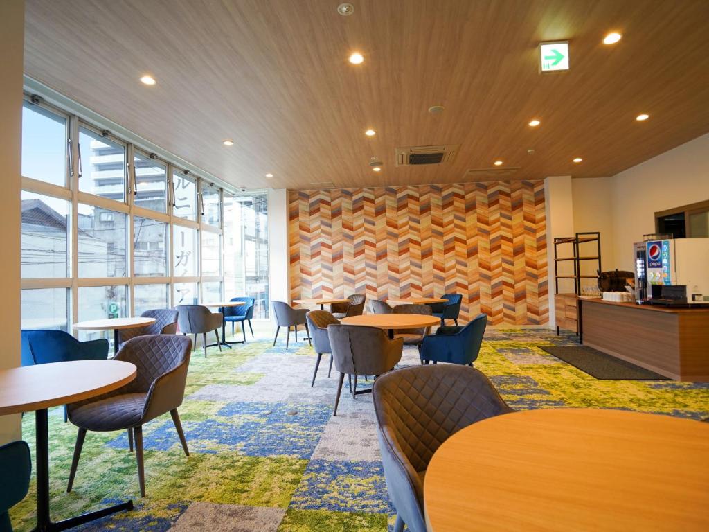 un restaurante con mesas y sillas y una pared de ventanas en Hotel New Gaea Iizuka, en Iizuka