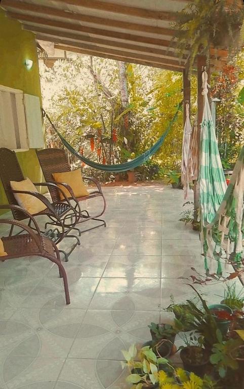 a patio with a hammock and chairs and flowers at Pousada Chalés Cantinho do Ronca - Paraty Mirim in Paraty