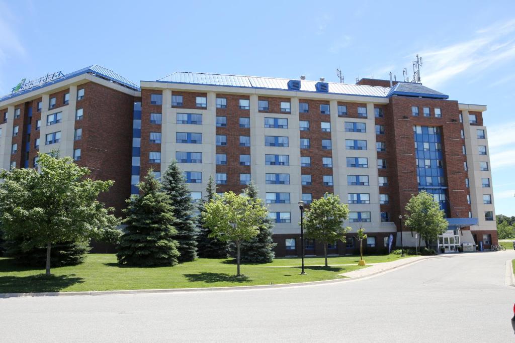 ein großes rotes Backsteingebäude mit Bäumen davor in der Unterkunft Residence & Conference Centre- Barrie in Barrie