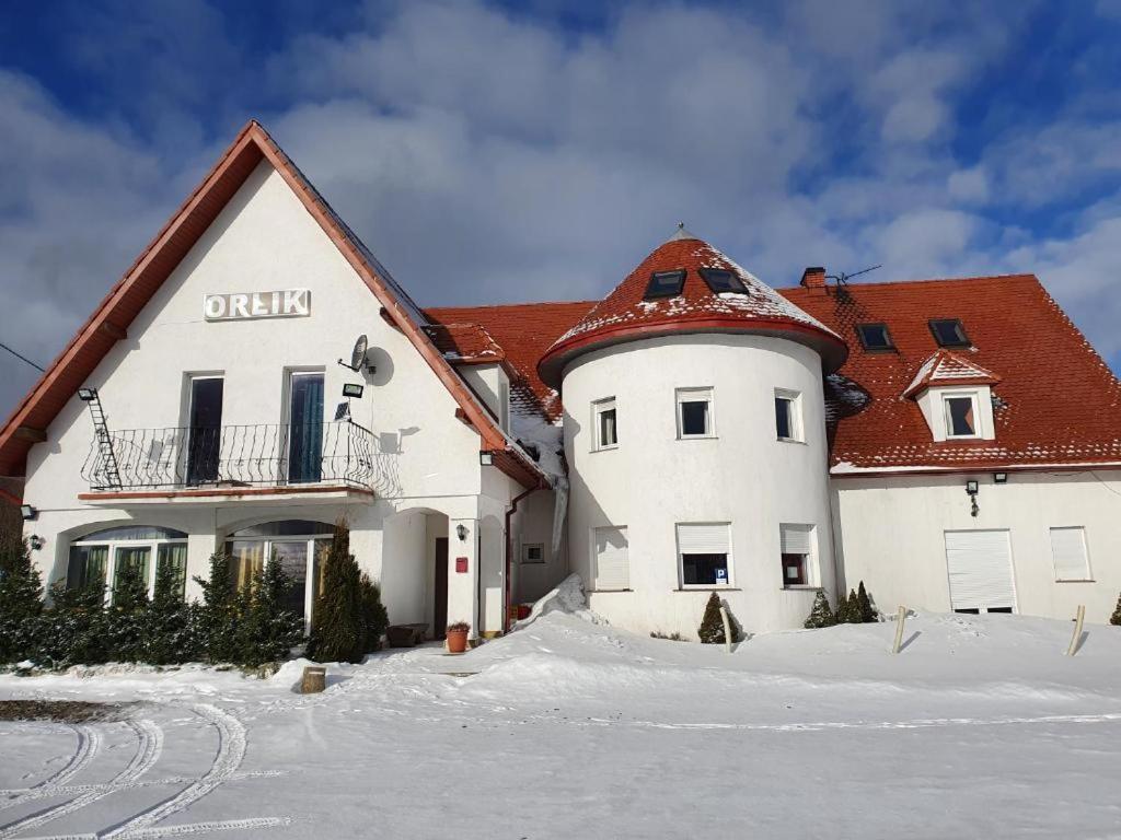 biały budynek z czerwonym dachem w śniegu w obiekcie Orlik by Good Spot w mieście Duszniki Zdrój