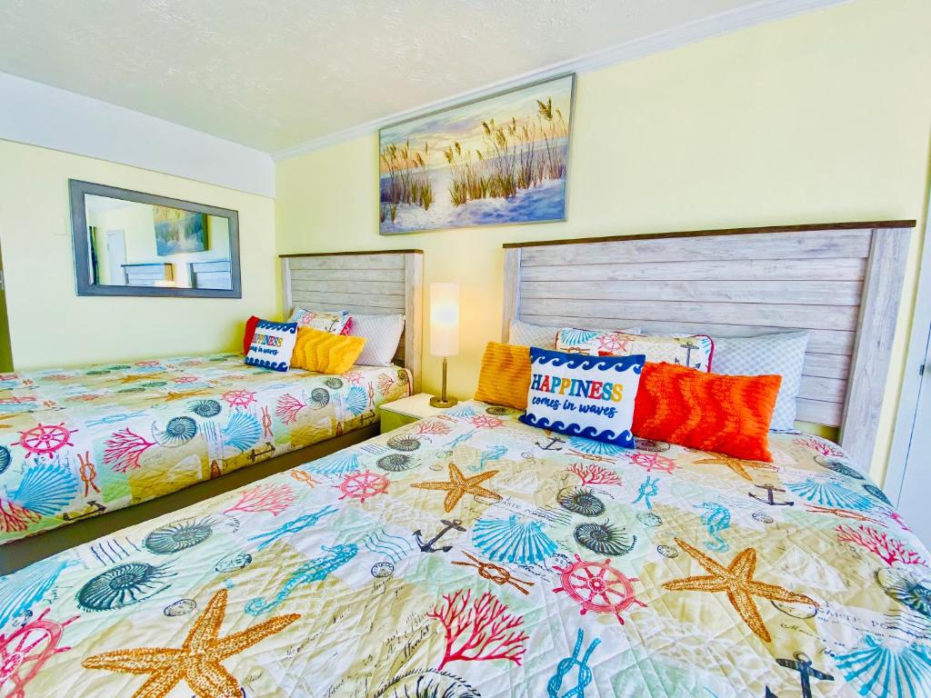 a bedroom with two beds with colorful pillows at Ocean Reef- Unique Oceanfront Condo-Free parking - Amazing pools in Myrtle Beach