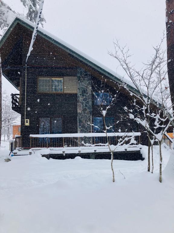 a house covered in snow in front at Ringo Cottage in Hakuba