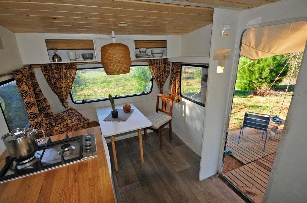 cocina y zona de comedor de una cabaña con mesa en Monte dos Vagabundos - Animal Sanctuary - Caravan nest en São Teotónio