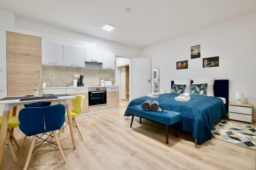 a bedroom with a blue bed and a kitchen at Standard Apartment by Hi5-Horváth Mihály square in Budapest