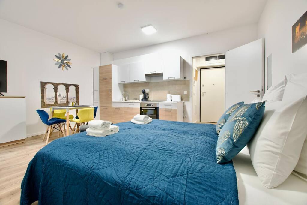 a bedroom with a blue bed and a kitchen at Standard Apartment by Hi5-Horváth Mihály square in Budapest