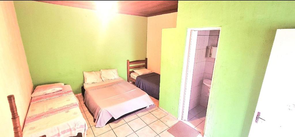 um quarto verde com 2 camas e um chuveiro em POUSADA VERDE em Caraguatatuba