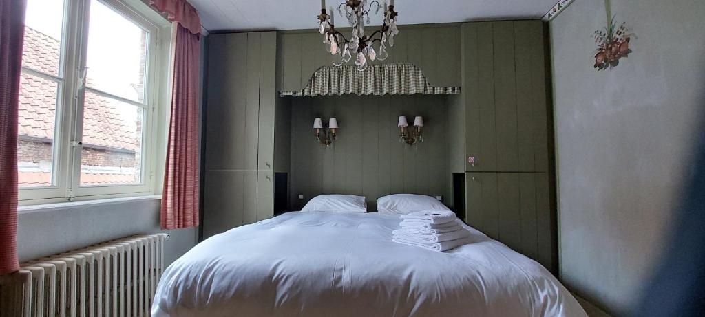 Un dormitorio con una cama con sábanas blancas y una lámpara de araña. en Heerlijke Studio in centrum van Brugge, en Brujas