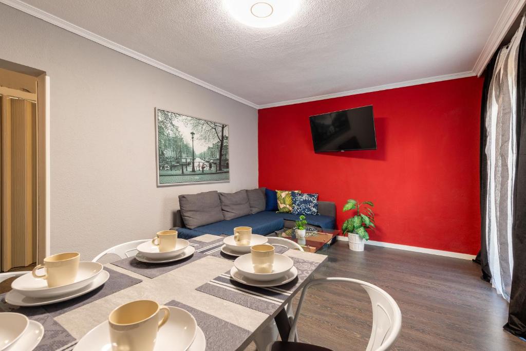 a living room with a table and a red wall at Apartamento Palacio Aranjuez Completo 2H - Warner Park Near in Aranjuez