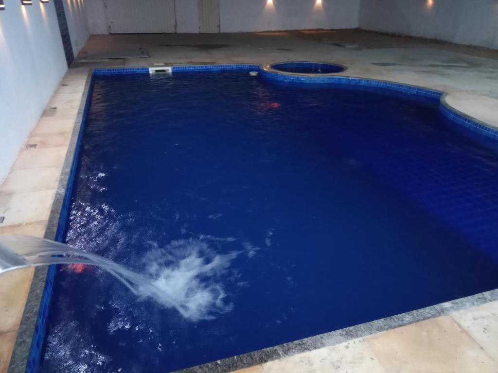 uma piscina com água azul e uma mangueira em Casa com Piscina, hidromassagem e churrasqueira. em Canoa Quebrada