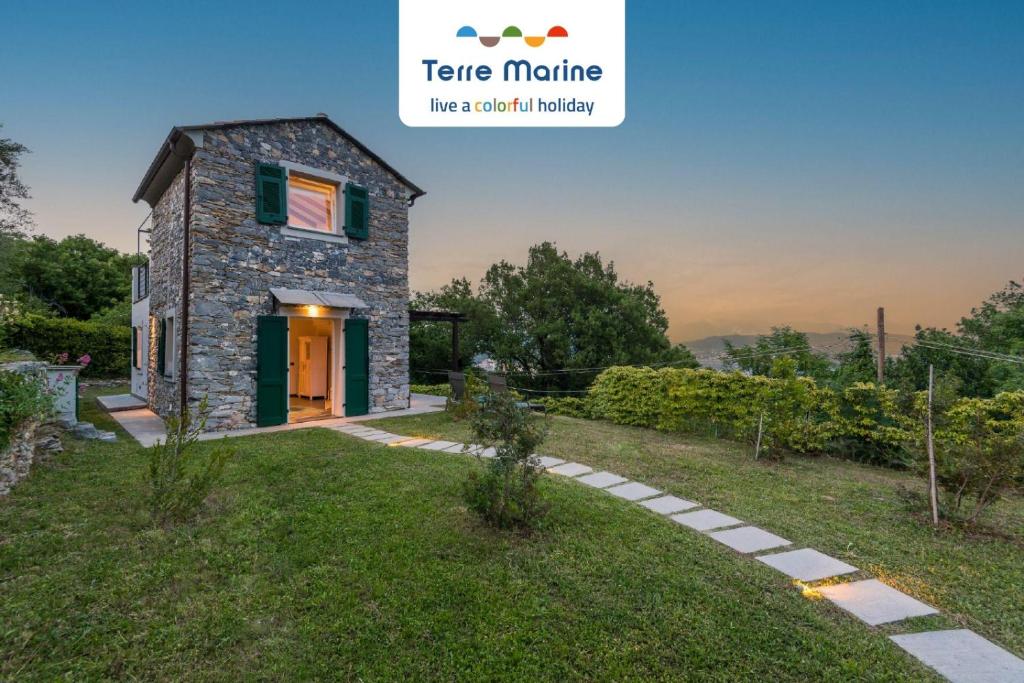 a small stone house with a green door on a grass field at Villa Ca Damare, TerreMarine in Le Grazie