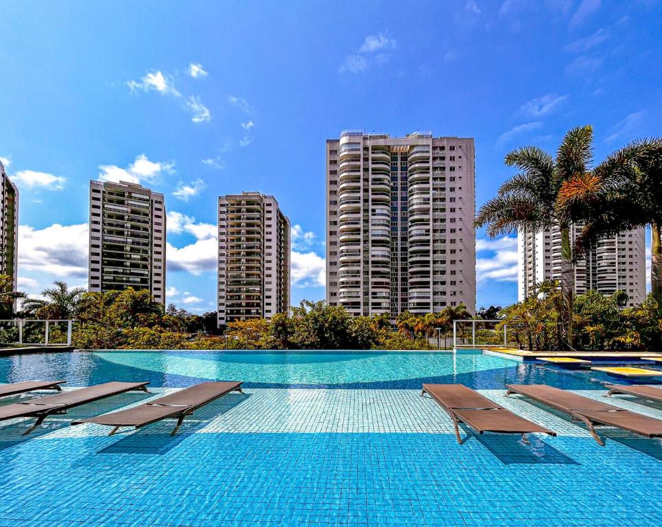 una gran piscina con sillas y edificios altos en Apto c vista p o mar e lagoa na Barra da Tijuca RJ, en Río de Janeiro