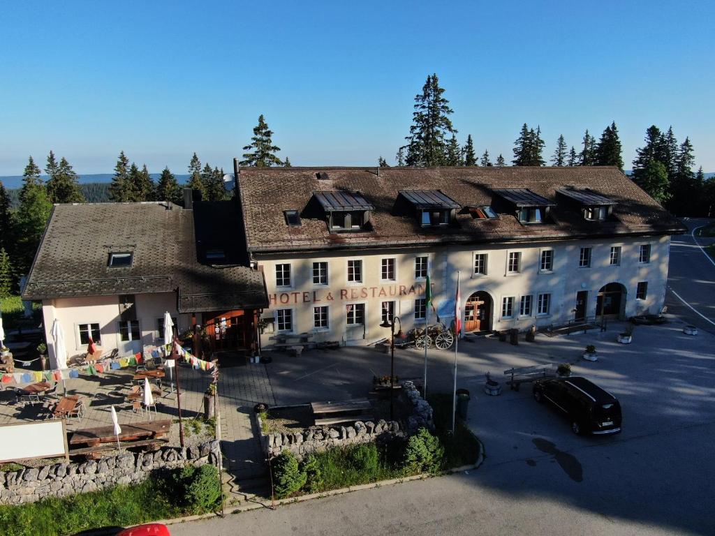 une vue aérienne sur un grand bâtiment avec un parking dans l'établissement Hôtel Restaurant du Marchairuz, à Le Brassus