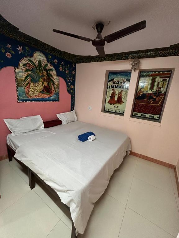 twee bedden in een kamer met schilderijen aan de muren bij Shyam Hostel in Jodhpur