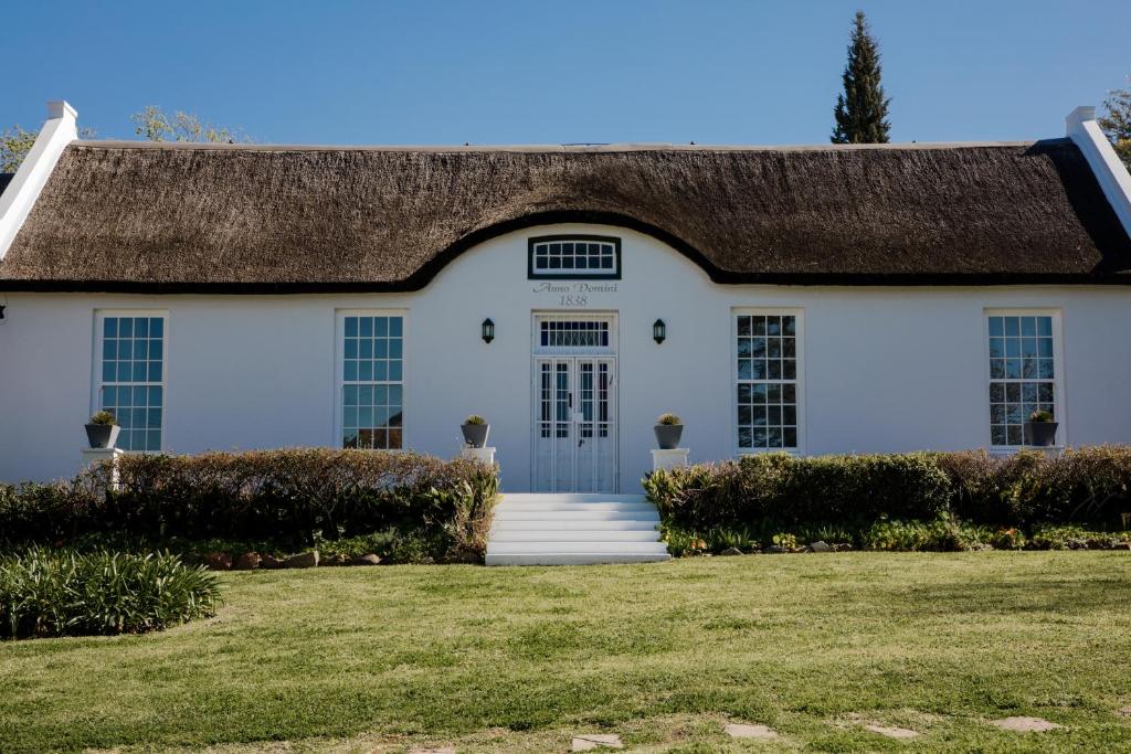 ein weißes Haus mit einem Strohdach in der Unterkunft La Sosta in Swellendam