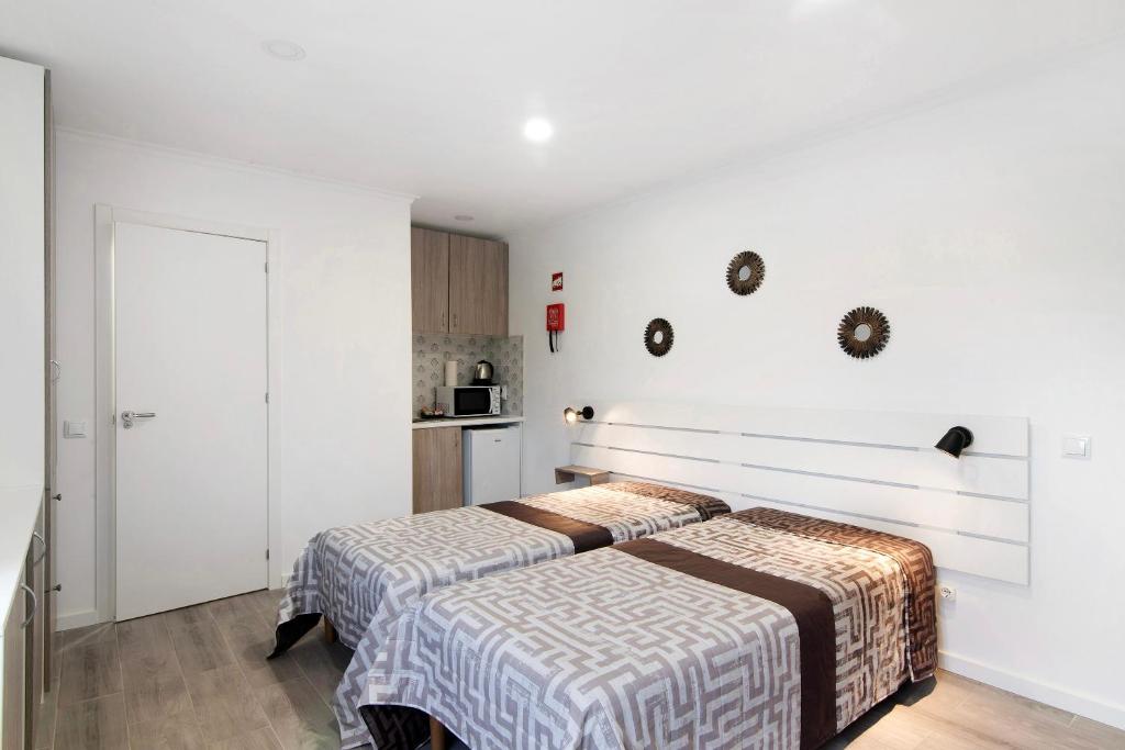2 Betten in einem Zimmer mit weißen Wänden in der Unterkunft Apartamento Mar in Moncarapacho