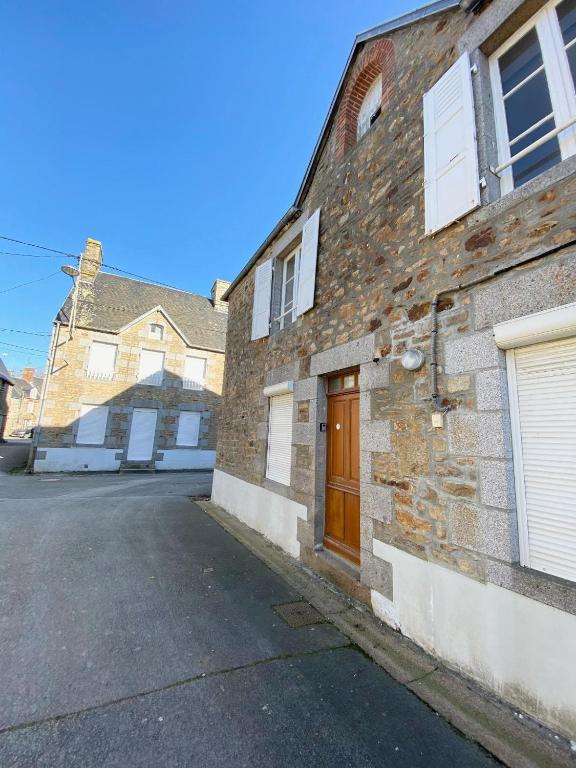 un bâtiment en briques avec une porte marron dans une rue dans l'établissement LES Herbus angle rue de l'avant-garde et 31 rue Jérémie, à Genêts