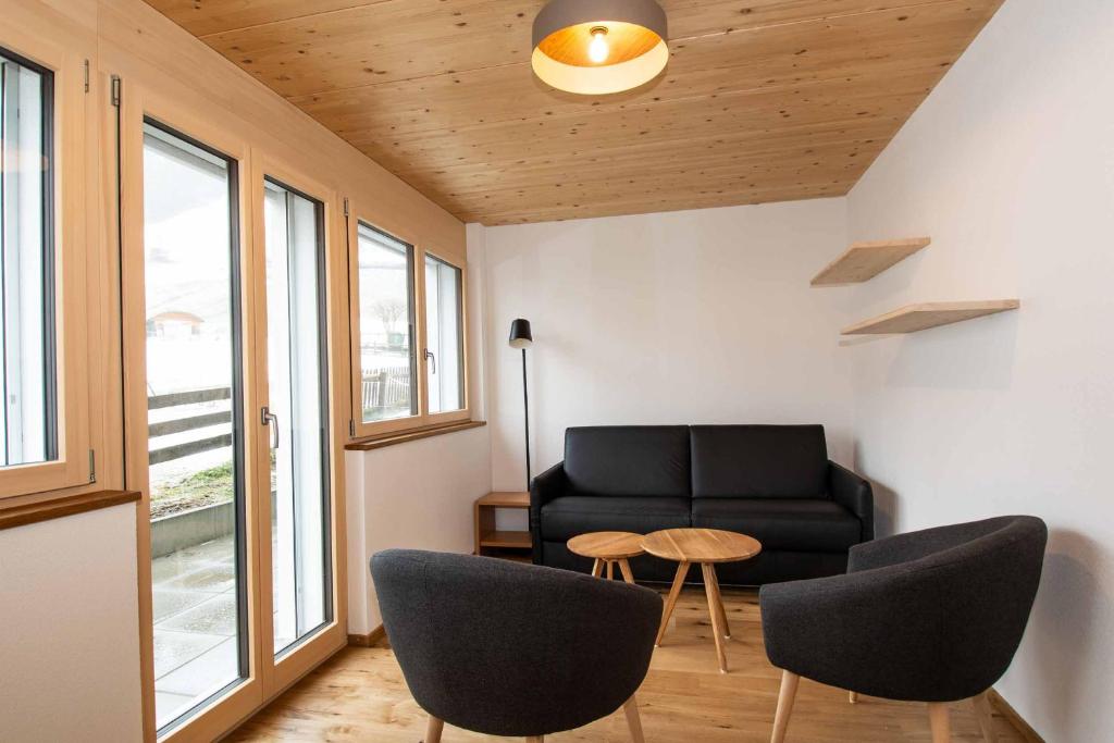 uma sala de estar com um sofá preto e cadeiras em Ferienchalet Sonne em Adelboden