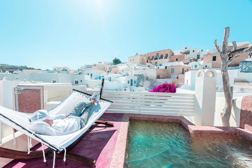 a woman laying in a hammock next to a swimming pool at Luxury Villas Hariton in Emporio Santorini