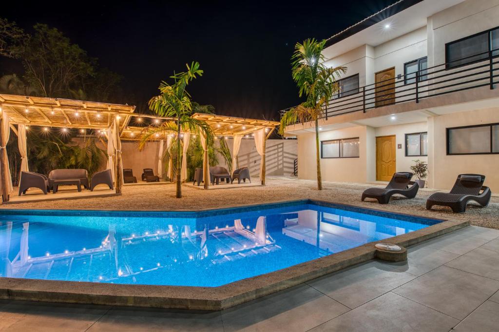 - une piscine en face d'une maison la nuit dans l'établissement Muna Santa Rosa Apartamentos, à Tamarindo