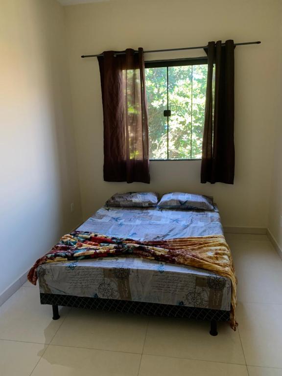a bed sitting in a bedroom with a window at Mini Casa 02 em Cabo Frio in Cabo Frio