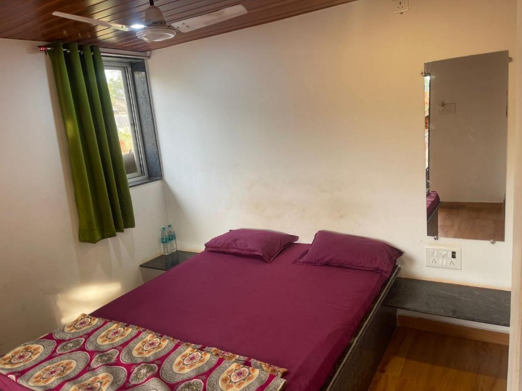 a bedroom with a bed with purple sheets and a window at Hemprabha Bed & Breakfast, Ratnagiri in Ratnagiri