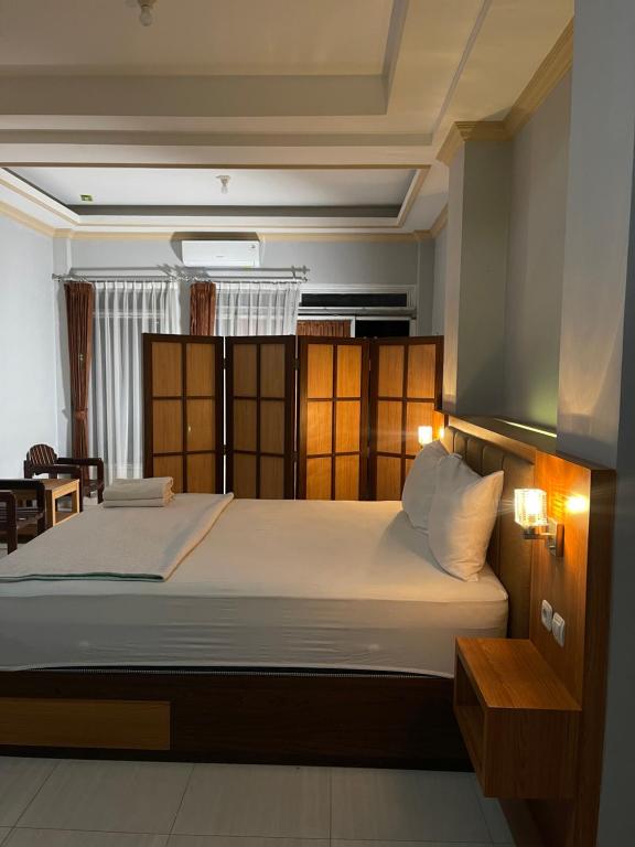 Wesbobo inn Solo في سولو: غرفة نوم مع سرير أبيض كبير في غرفة