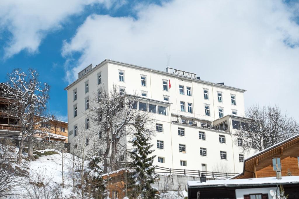 Un bâtiment blanc avec un drapeau en haut dans l'établissement Boutique-Hotel Garni Bellevue Davos Wiesen, à Wiesen