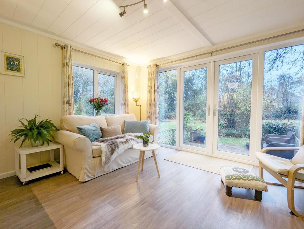 a living room with a couch and large windows at Red Oak - Bosham in Bosham