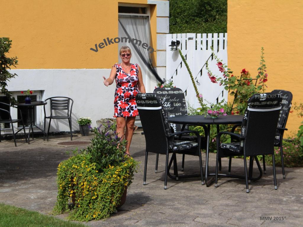 a woman standing in front of a table and chairs at Murermester Madsens Villa in Otterup