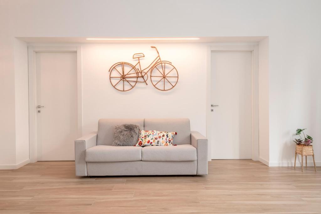 een woonkamer met een bank en een fiets aan de muur bij Tree Apartment BG in Bergamo