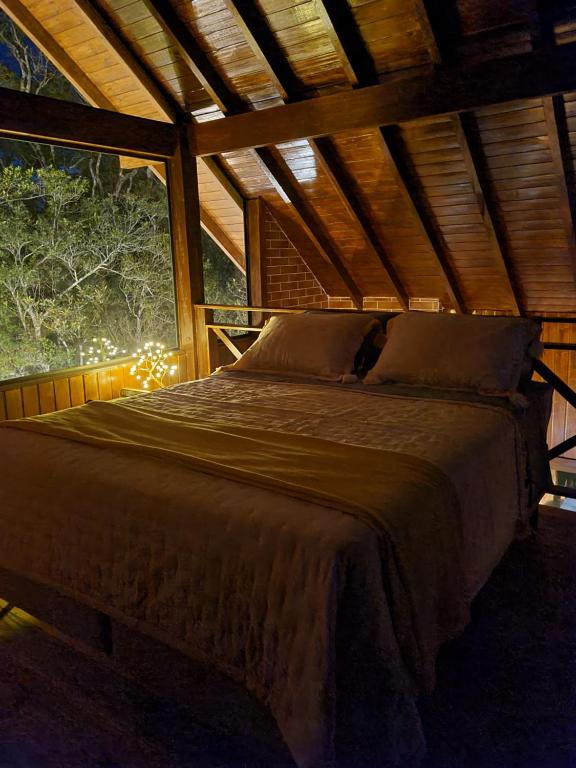 uma cama grande num quarto com uma janela grande em Chalé Romântico em São Francisco de Paula