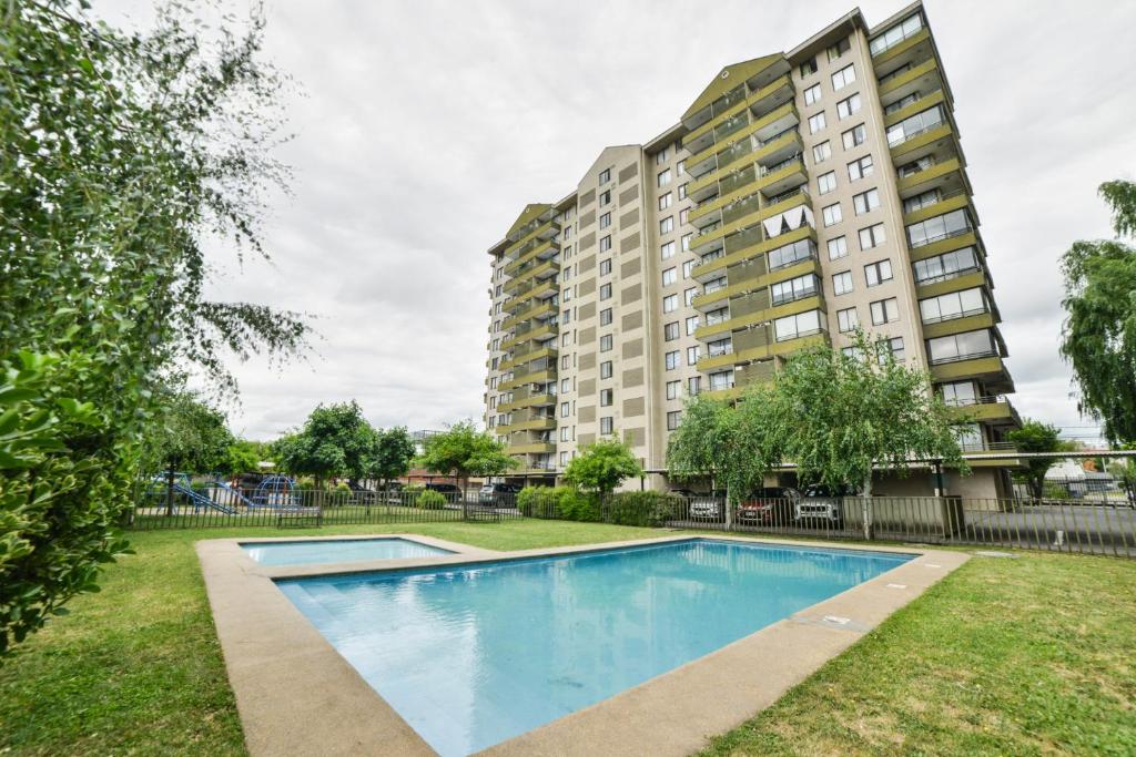an empty swimming pool in front of a building at Home Apartments in Los Ángeles