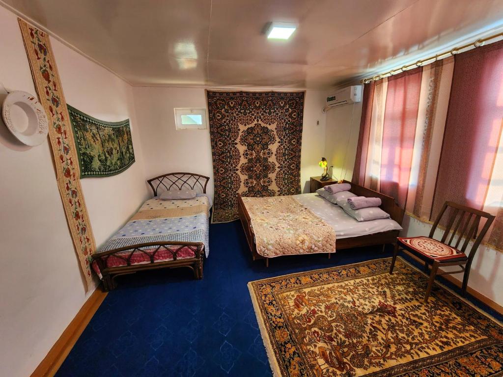 a bedroom with two beds and two chairs and a rug at Zafar Family Guesthouse in Bukhara