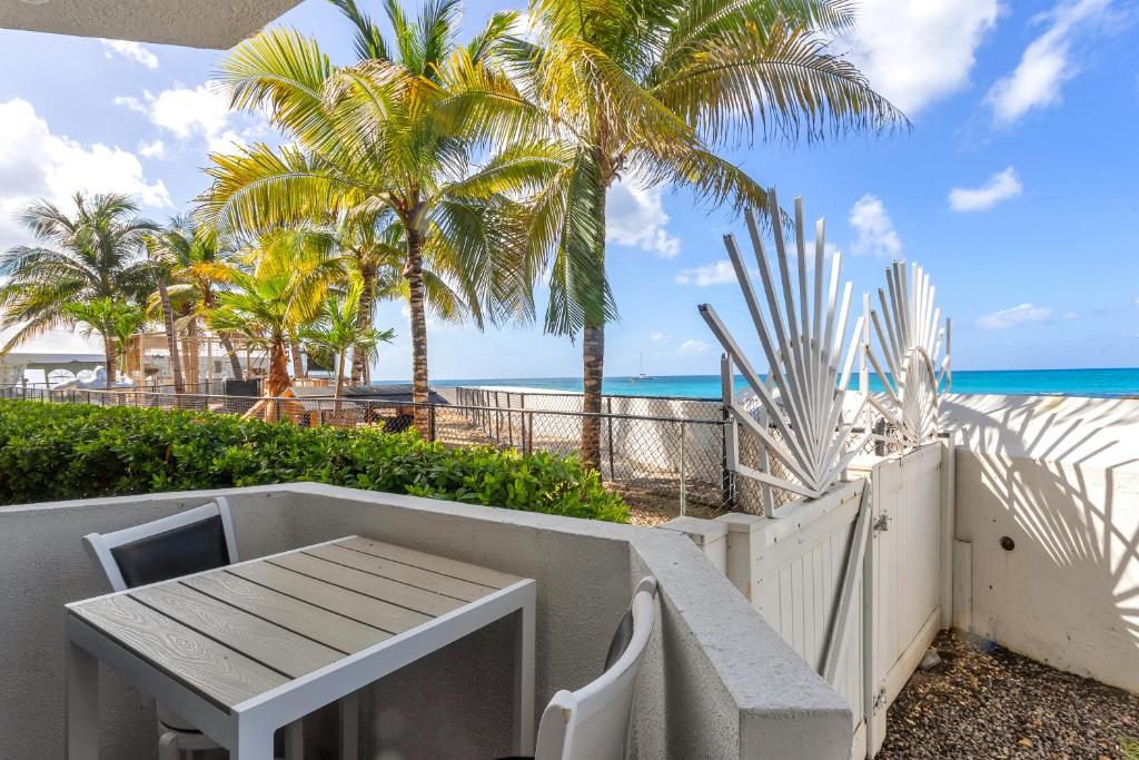 einen Tisch und Stühle am Strand mit Palmen in der Unterkunft The Best Little Beach Bar Condo next to The Morgan Village in Maho Reef