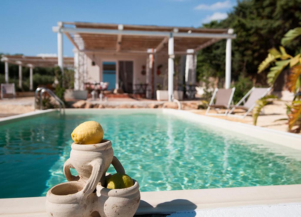a statue of a person holding fruit next to a swimming pool at Jabia Beach House in Marinella di Selinunte