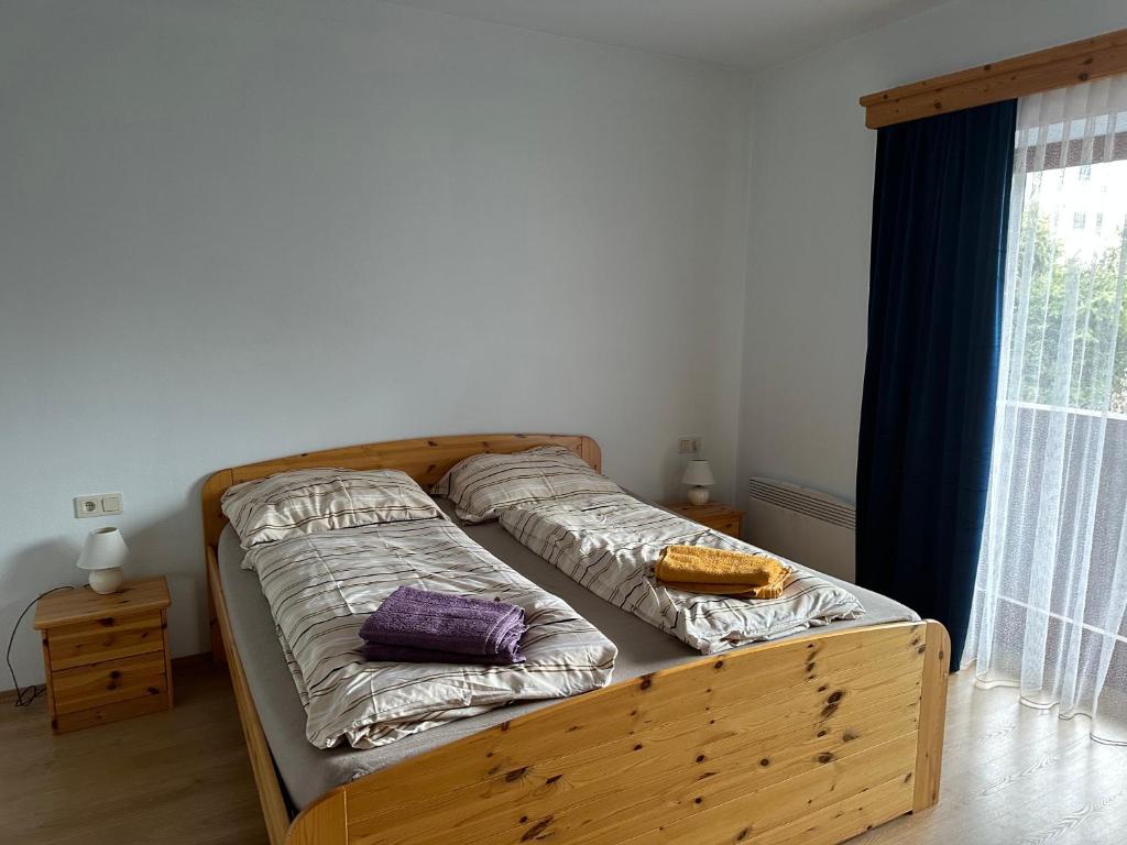 1 cama con marco de madera en una habitación con ventana en Sissi Apartment en Ausserfragant
