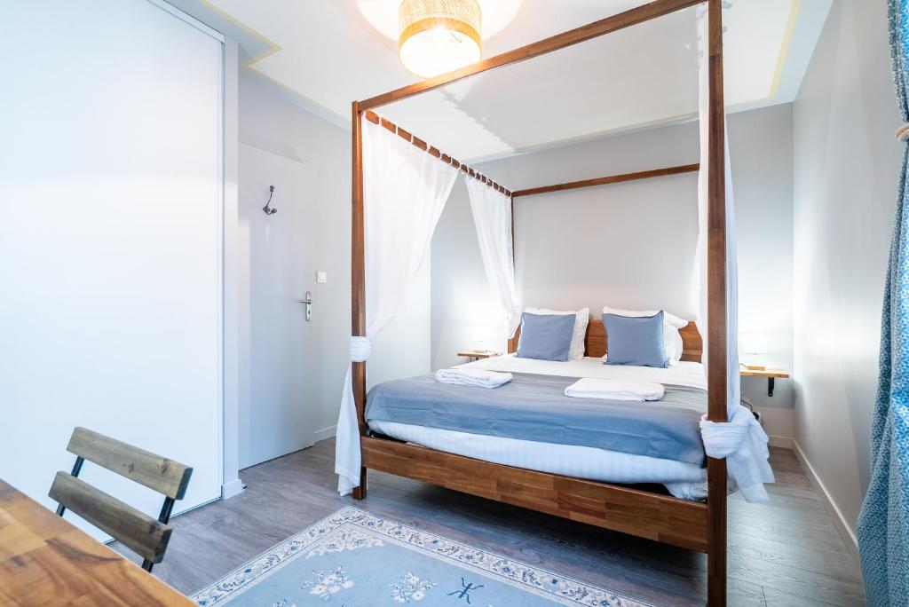 a bedroom with a canopy bed with blue sheets and pillows at Mon Appart'hôtel - Gare de Limoges - Charmant 1 et 2 Chambres Duplex - Parking en supp in Limoges